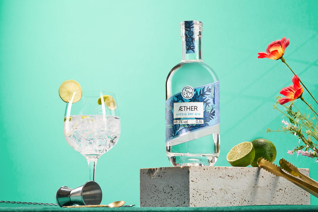 Heller Gin in Glasflasche mit weißen Blüten und weichem Tageslicht